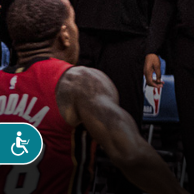 African American man in the background wearing a red sleeveless jersey. In the foreground is the accessibility button which is turquoise with the wheelchair users symbol in white
